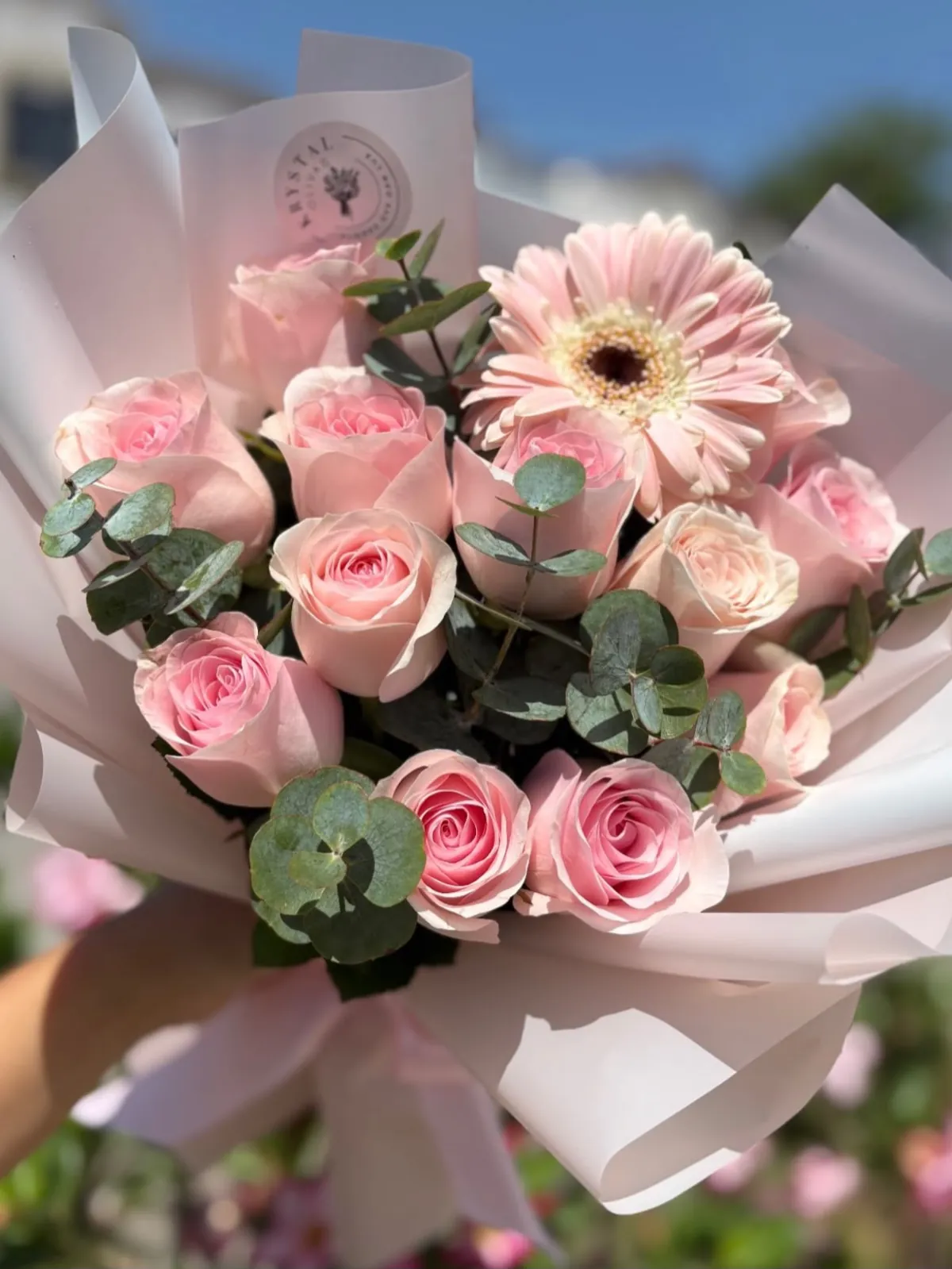 Ramo de rosas rosa claro con gerbera y eucalipto sobre papel blanco